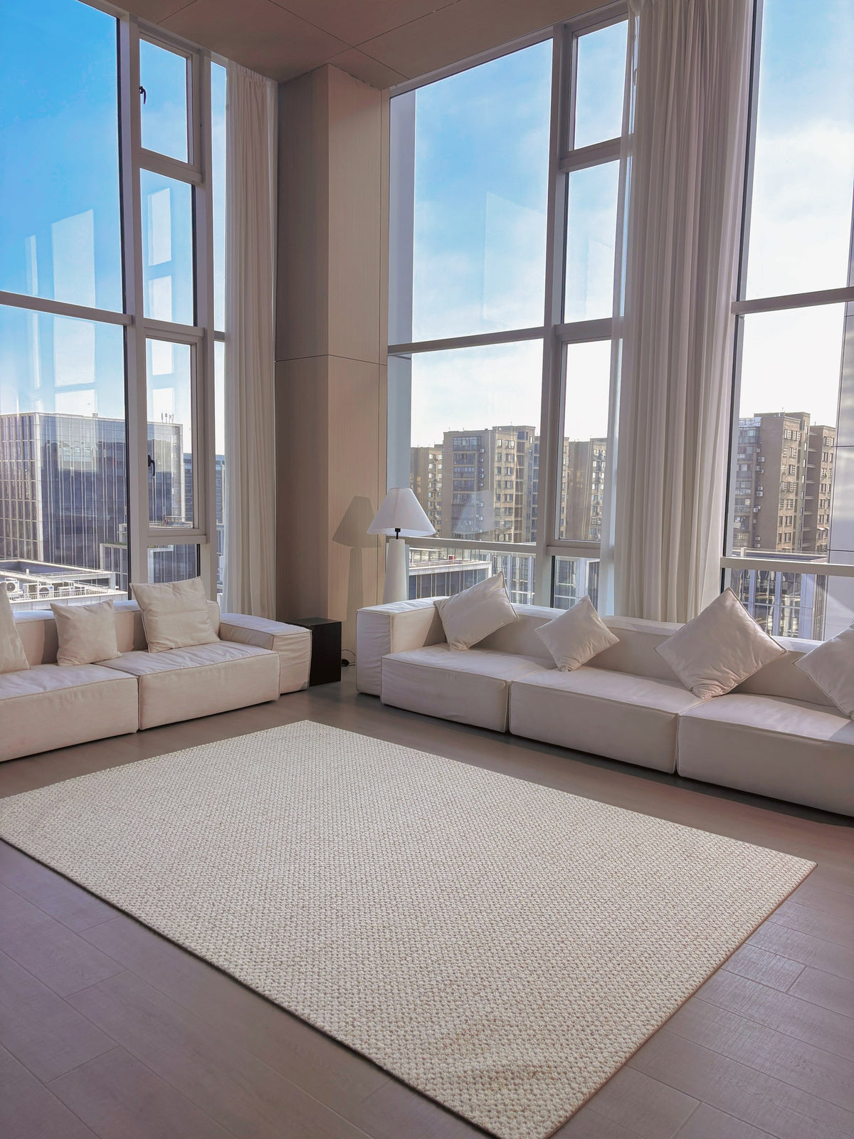 Dapple rug in a double-height living room with white sofas and tall windows.