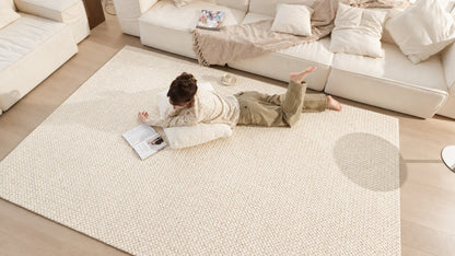 Looking down on the Dapple rug in front of a white sofa, with someone reading on it.