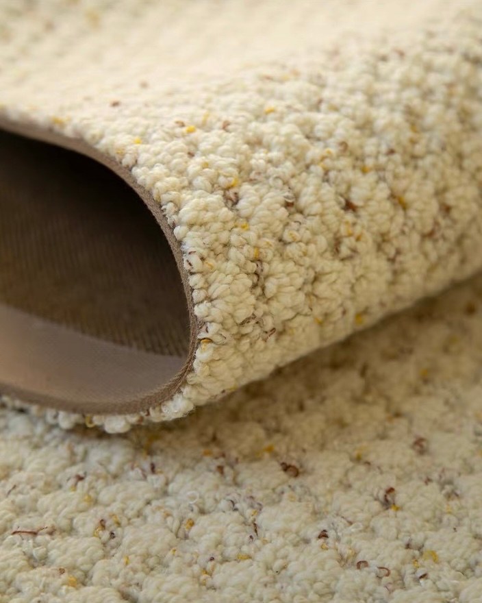 Dapple rug rolled back to show its brown backing and flecked cream pile.