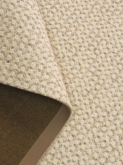 Corner of the Dapple rug folded over, showing its textured loops and backing.