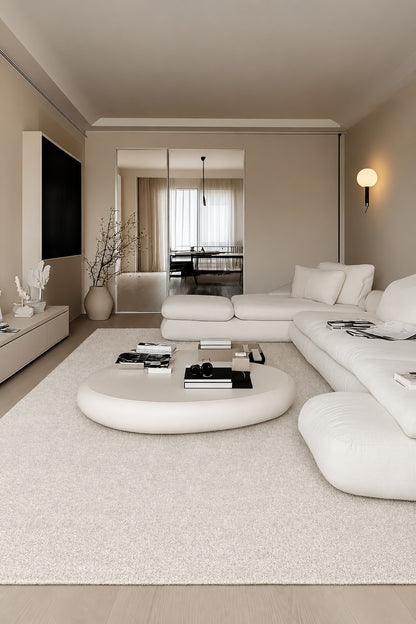 Daybreak rug in a long, minimal living room with a white modular sofa and round coffee table.