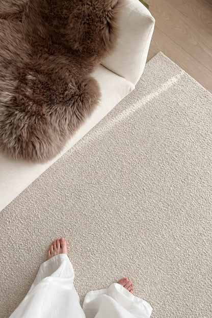 Looking down at bare feet on the Daybreak rug beside a white sofa and a sheepskin.