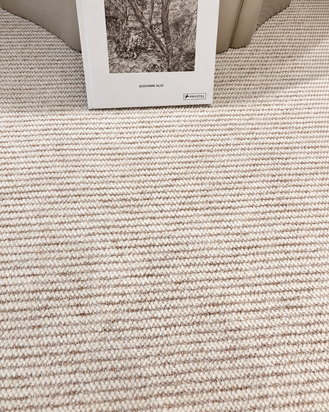 Close-up of the Glint rug's ribbed texture, with an art book propped against a sofa.
