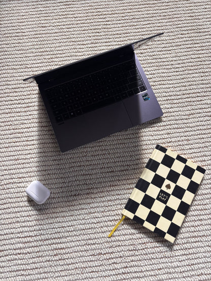 Laptop, notebook and earbuds case resting on the ribbed Glint rug.