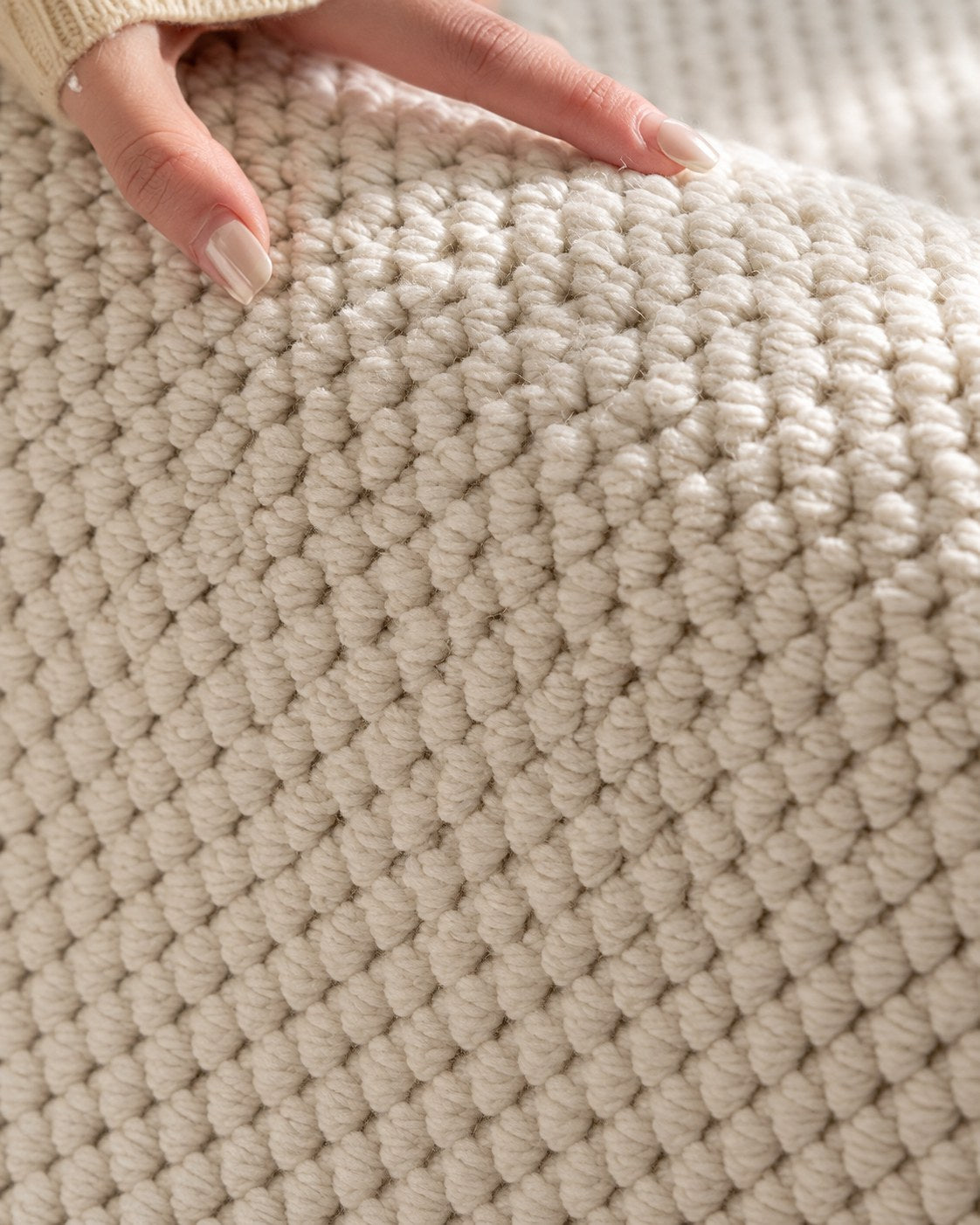 Hand resting on the Halcyon rug, showing its chunky ivory loop texture up close.