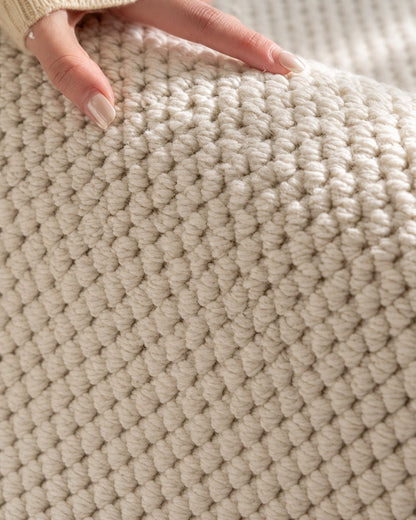 Hand resting on the Halcyon rug, showing its chunky ivory loop texture up close.