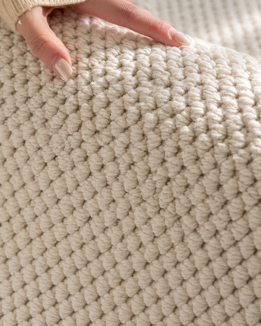 Hand resting on the Halcyon rug, showing its chunky ivory loop texture up close.