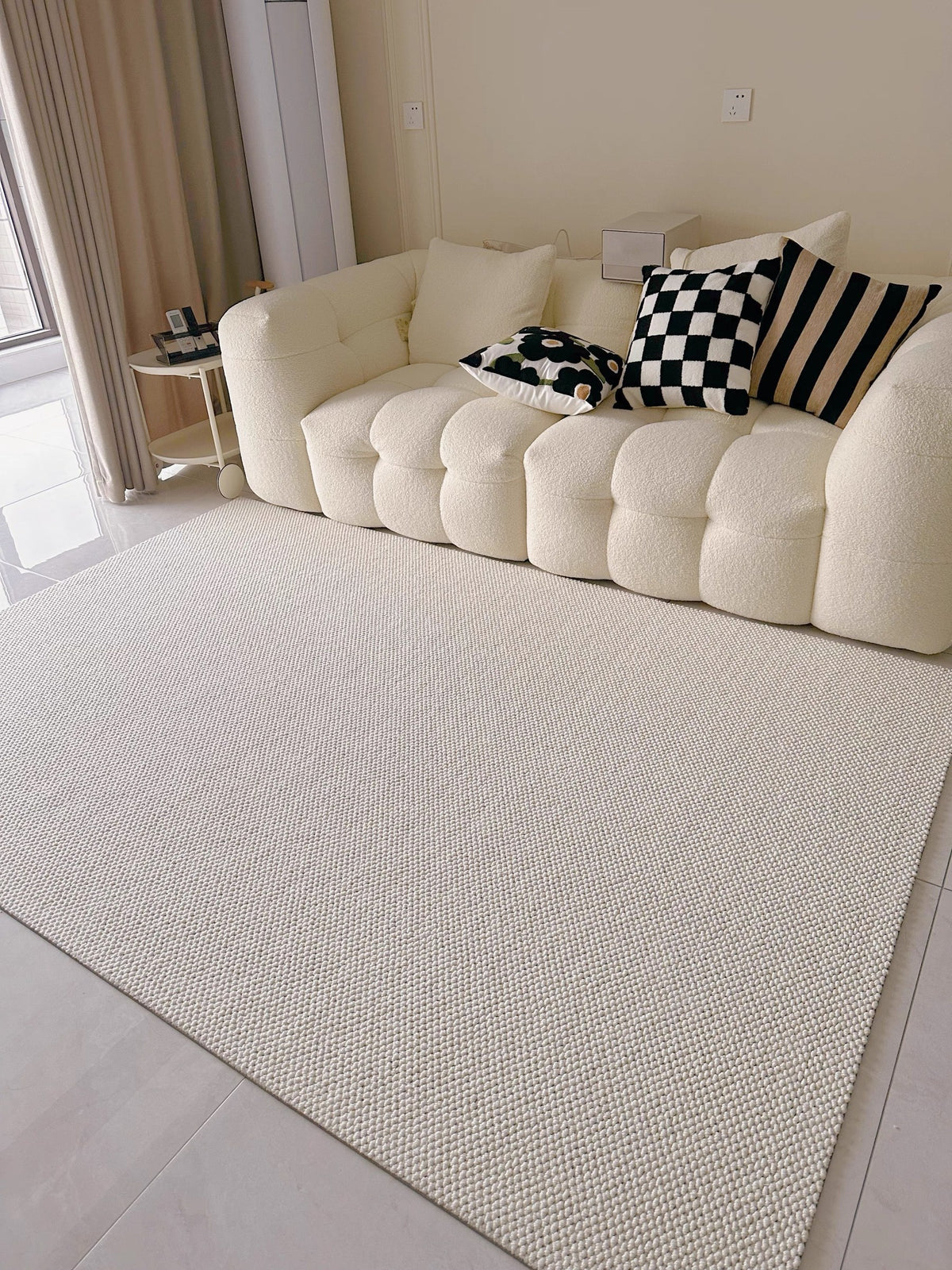 Halcyon rug in front of a cream bouclé sofa with black-and-white cushions.