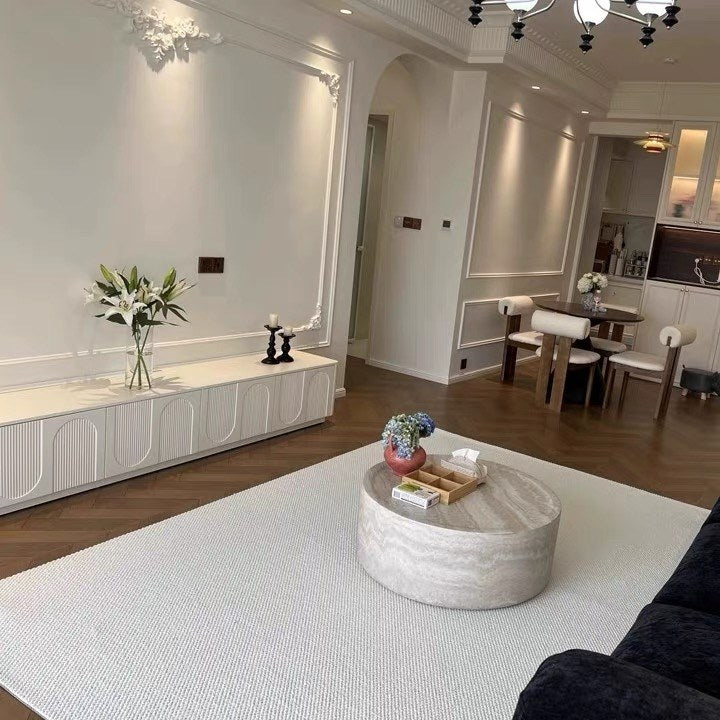 Halcyon rug under a round travertine coffee table in a white living room.
