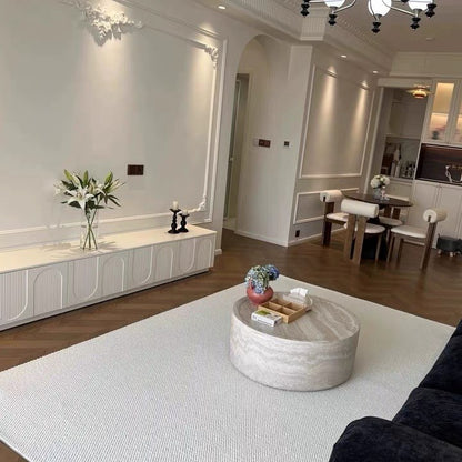 Halcyon rug under a round travertine coffee table in a white living room.