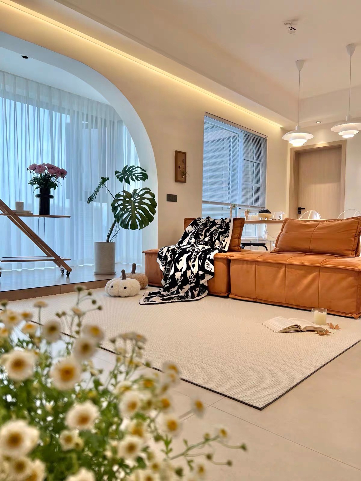 Halcyon rug in an open living room with an orange leather sofa and daisies in the foreground.