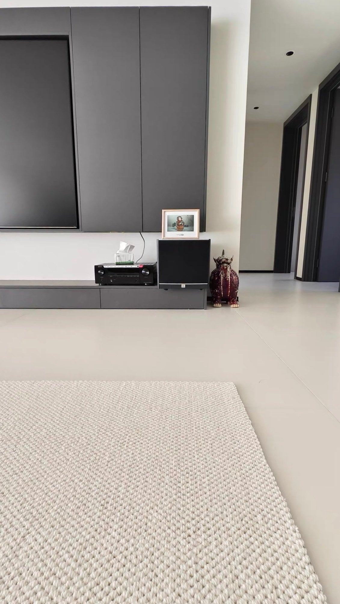 Edge of the Halcyon rug on a pale tiled floor in a modern living room.