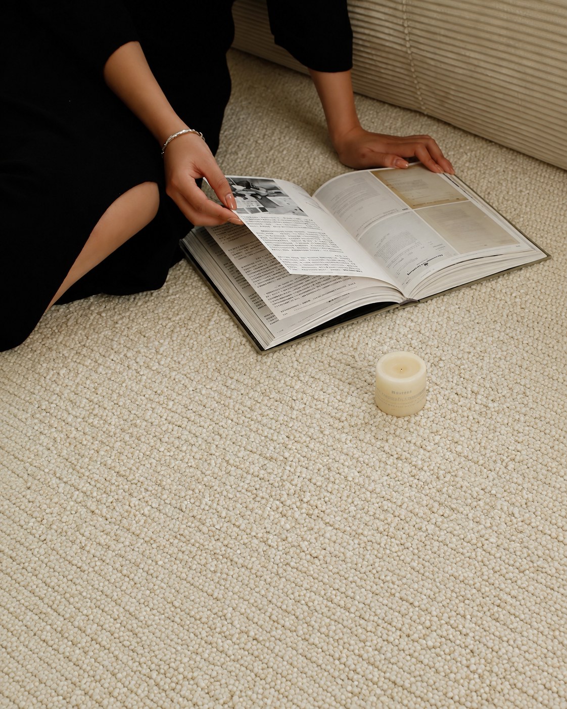 Someone reading a magazine on the Sunlit rug beside a candle.