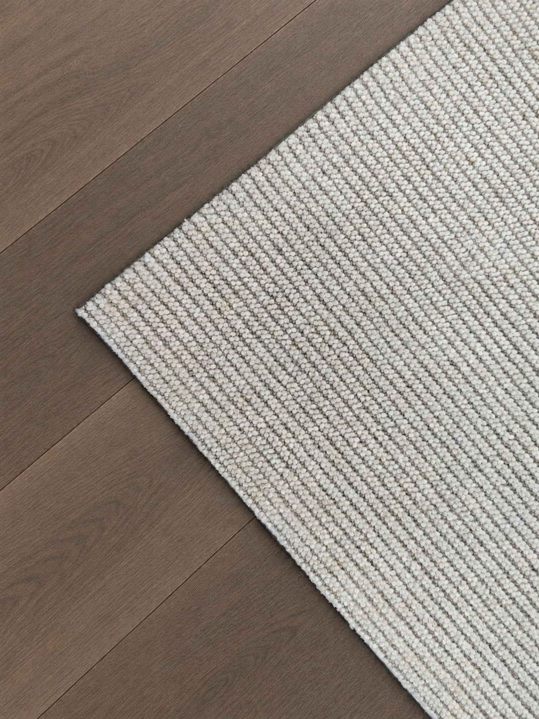 Corner of the Vesper rug on a timber floor, showing its cream and taupe corded surface.